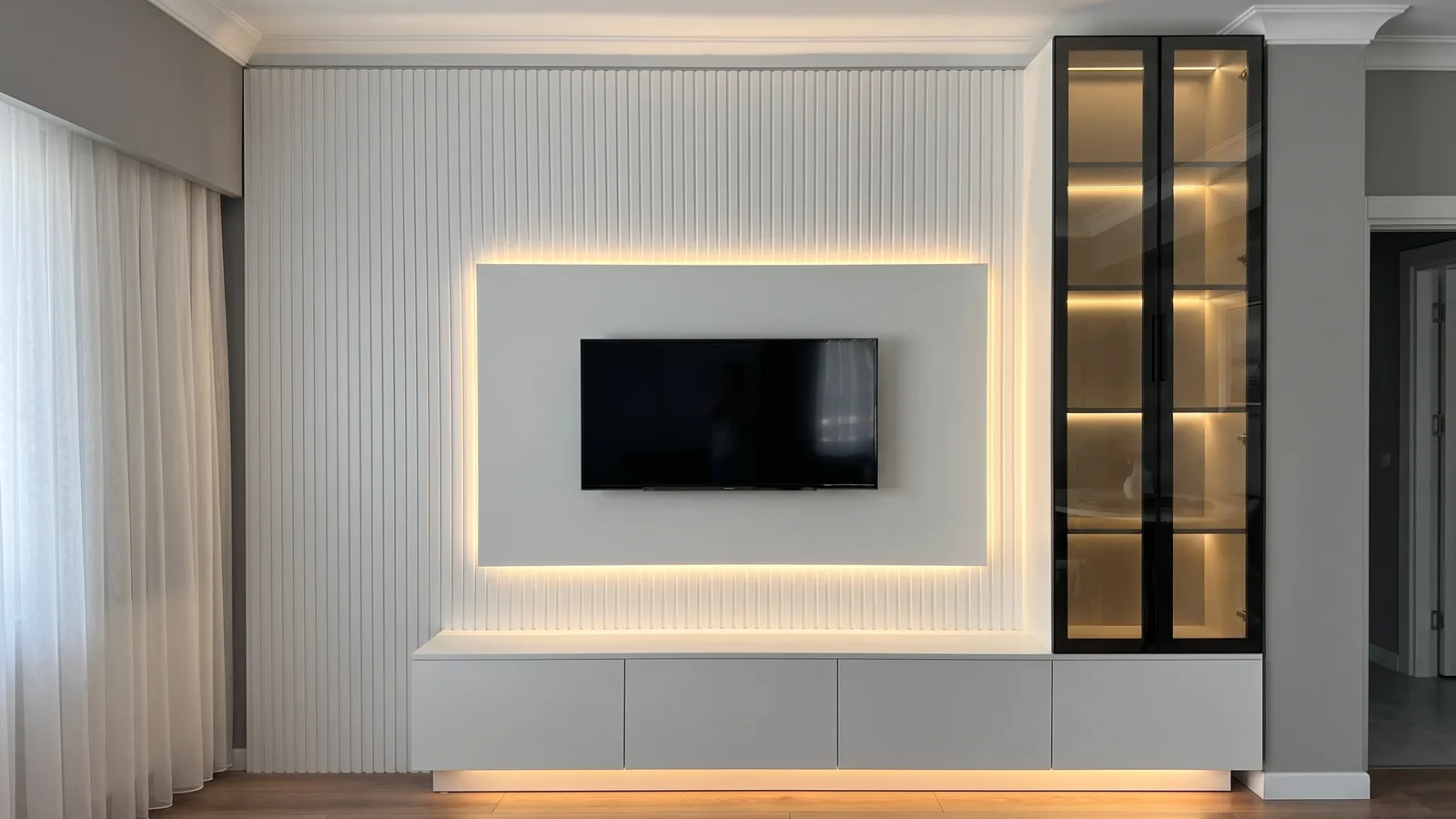 Sala pronta: parede ripada branca, painel liso com LED em volta da TV, rack suspenso cinza-claro com LED por baixo e cristaleira de vidro fumê com perfil preto até o teto